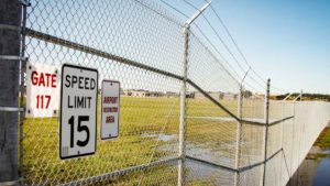 Tall security chain link fence enclosure topped with barbed-wire